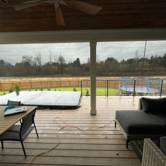Covered patio with fenced backyard and trampoline view.