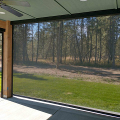 Patio with screen overlooking wooded area and grass.