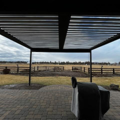 Covered patio with view of open field and sky.