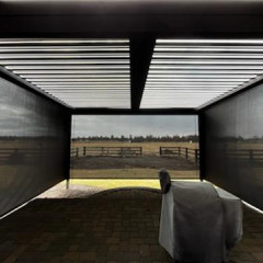 Covered patio overlooking grassy field and fences.