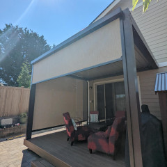 Outdoor patio with chairs under sunshade.