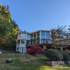 Modern house with large windows surrounded by trees.